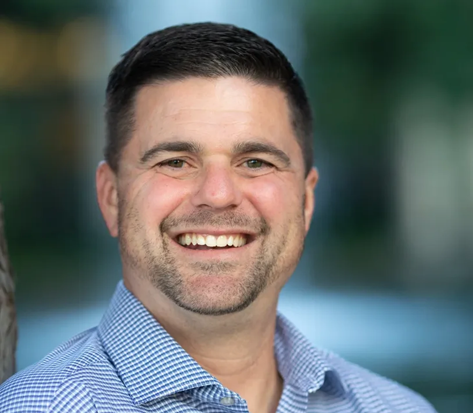 Portrait of Travis Catania, Managing Partner at Masswell Capital Advisors, smiling outdoors in a casual business shirt